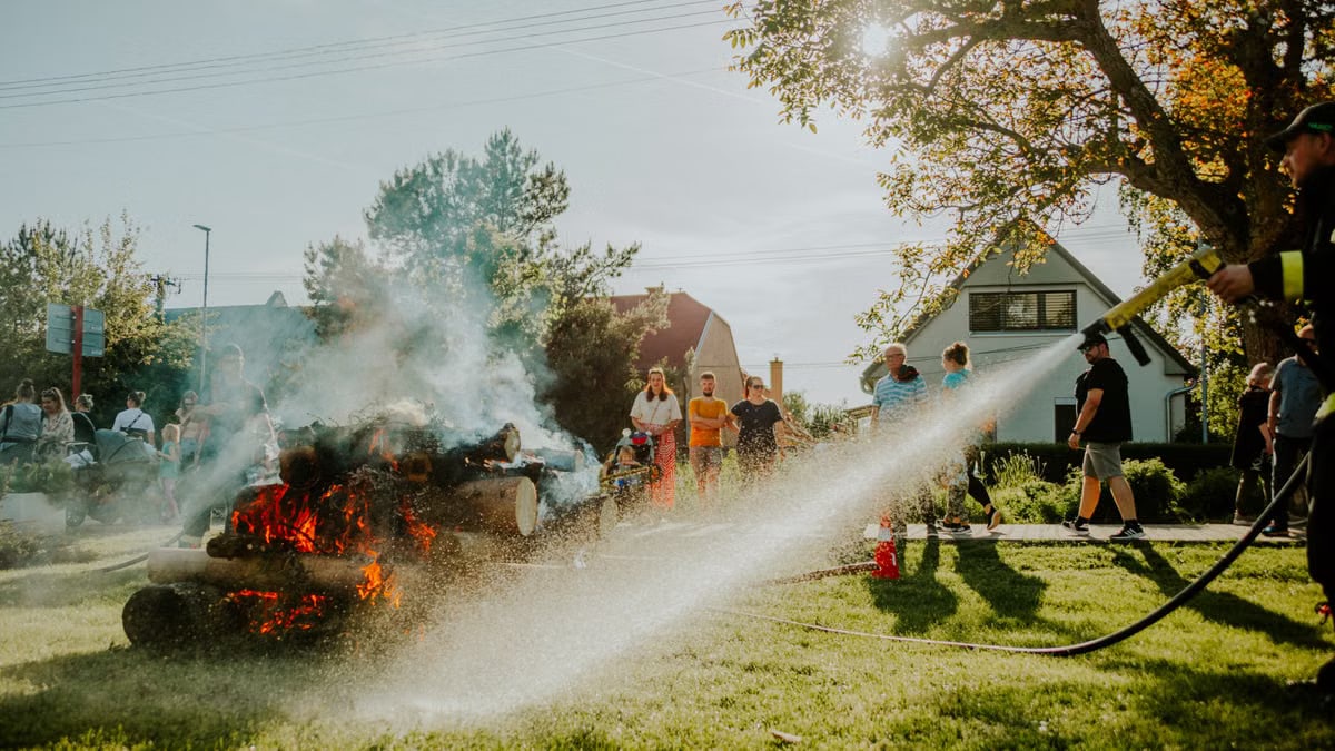Firefighter showcases safety techniques on a controlled fire at a community event in the park.